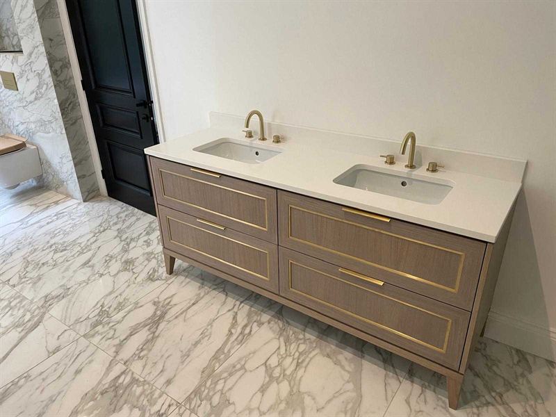 Twin basin vanity unit with brass taps set against marble tiling