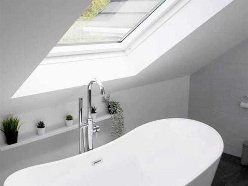 Freestanding bath positioned beneath a roof window in a loft bathroom