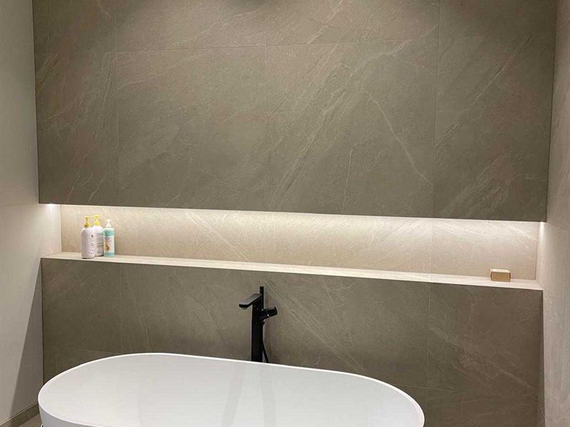 Freestanding bath below an illuminated recessed wall niche
