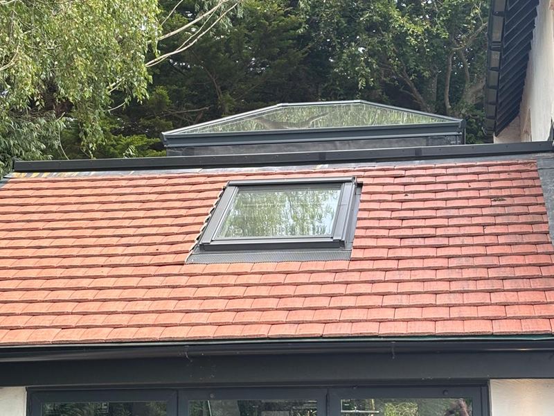 Clay tiled extension roof fitted with a roof window and a glazed lantern behind