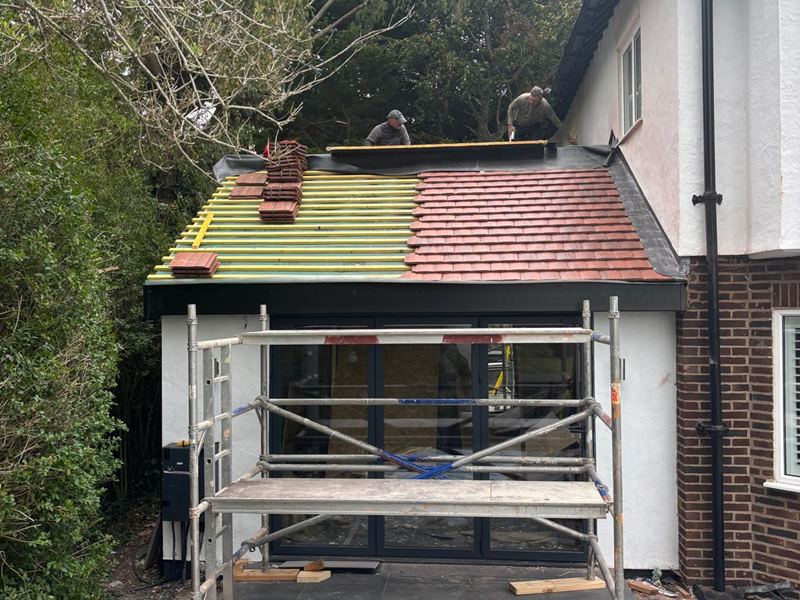 New extension part way through roofing, with clay tiles being laid over battens and membrane