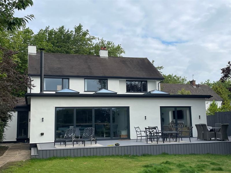 White rendered rear extension with bi-fold doors, three roof lanterns and raised grey decking