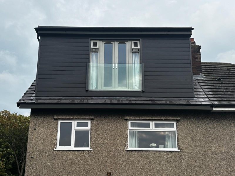 Completed loft conversion with an anthracite clad box dormer, French doors and a glass Juliet balcony