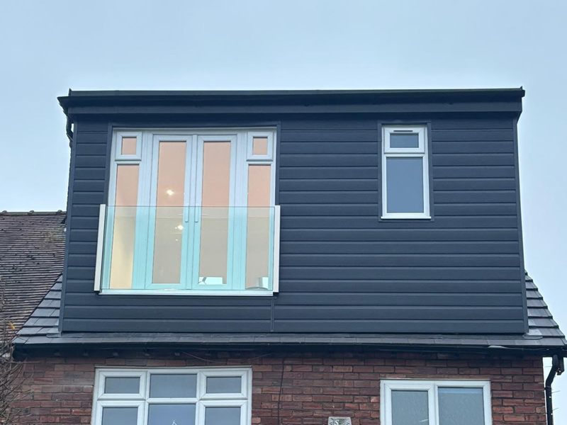 Finished dark clad dormer with a glass Juliet balcony on the rear of a red brick semi detached house