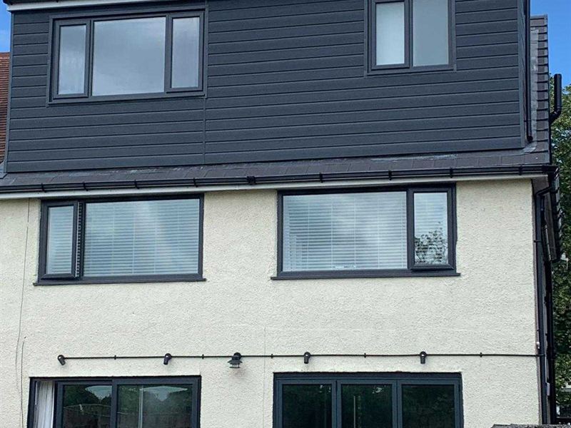 Completed loft conversion with a full width dormer clad in grey, above a white rendered house