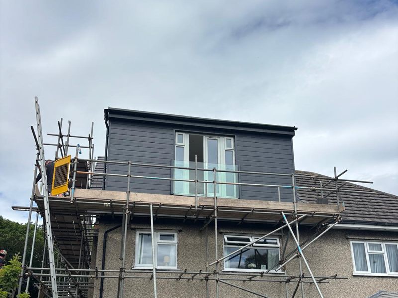 Grey clad dormer loft conversion completed to the rear of a pebbledash semi, with scaffolding still in place