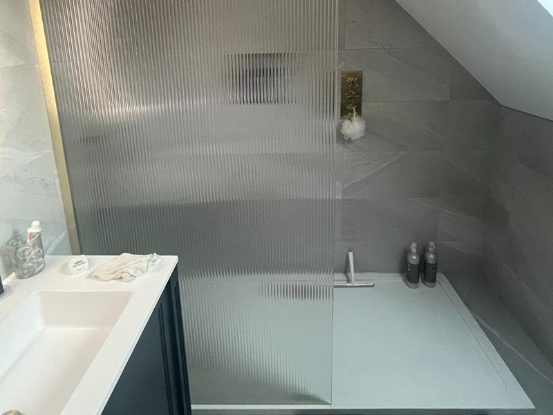Loft shower room with a fluted glass screen and a low profile shower tray tucked in under the eaves