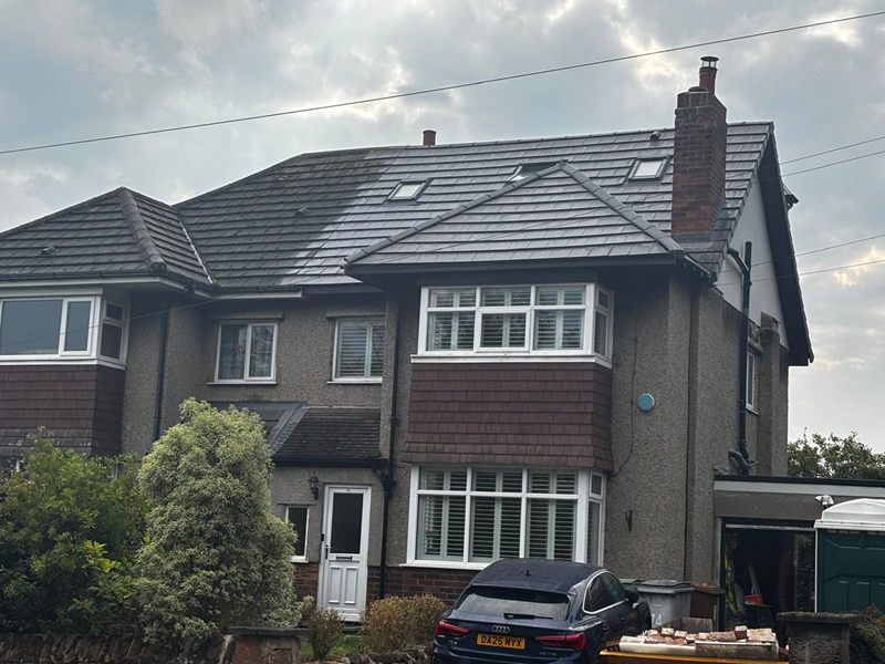 Front elevation of a completed loft conversion and full re-roof, with new dark tiles and rooflights