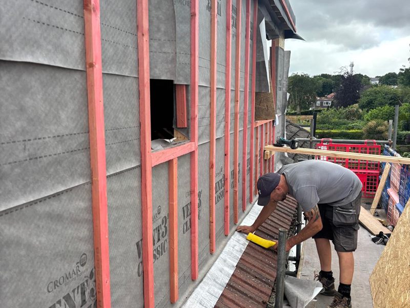 Roofer working along the edge of a new dormer battened out over breather membrane