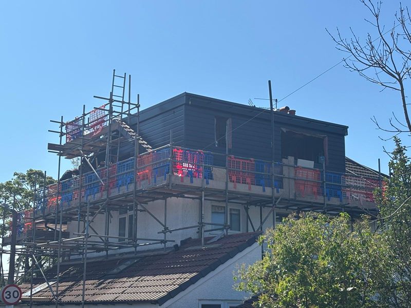 Loft conversion dormer clad in dark grey behind scaffolding, with the roof still to be finished