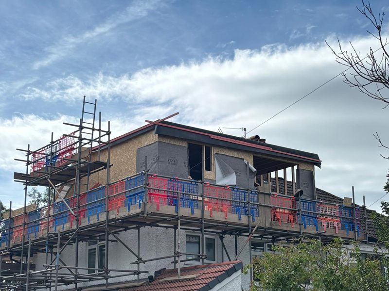 New dormer framed and sheathed in board and breather membrane, seen from the road behind scaffolding