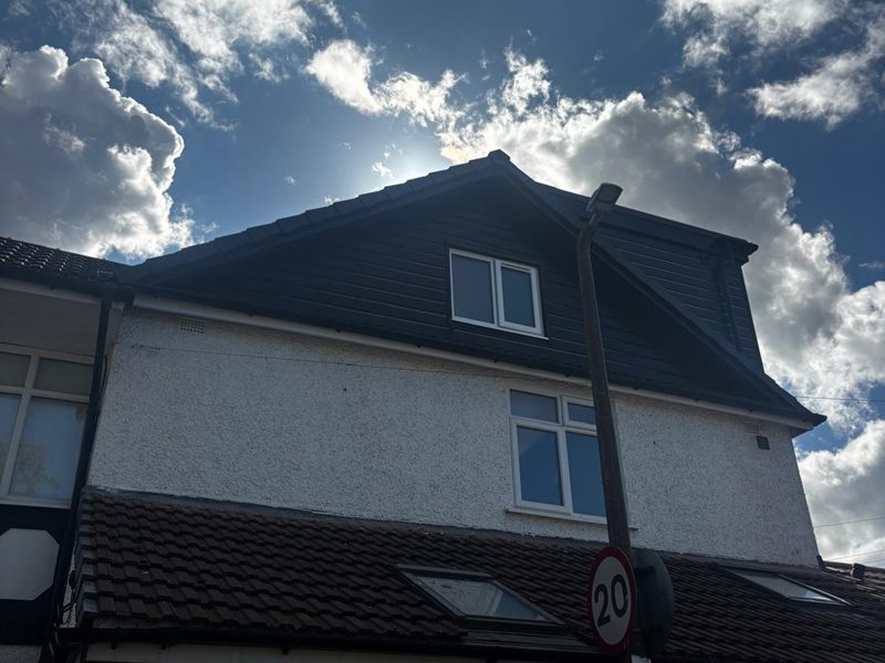 Finished gable end of a Heswall loft conversion, clad in dark grey with new windows