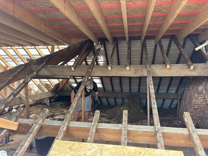 Inside a loft during strip out, with the original roof timbers exposed and new floor joists going in