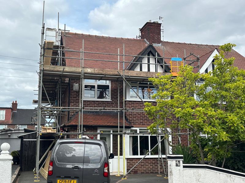 Scaffolding erected across the front of a red brick semi at the start of a loft conversion