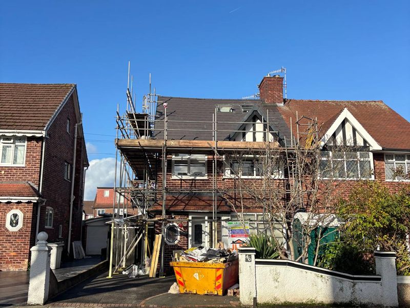 Street view of a scaffolded semi with its loft conversion roof re-covered in dark tiles