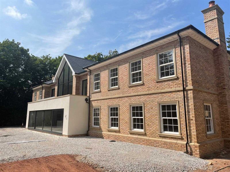 Detached new build in red brick with a gabled entrance bay and a wide gravel driveway