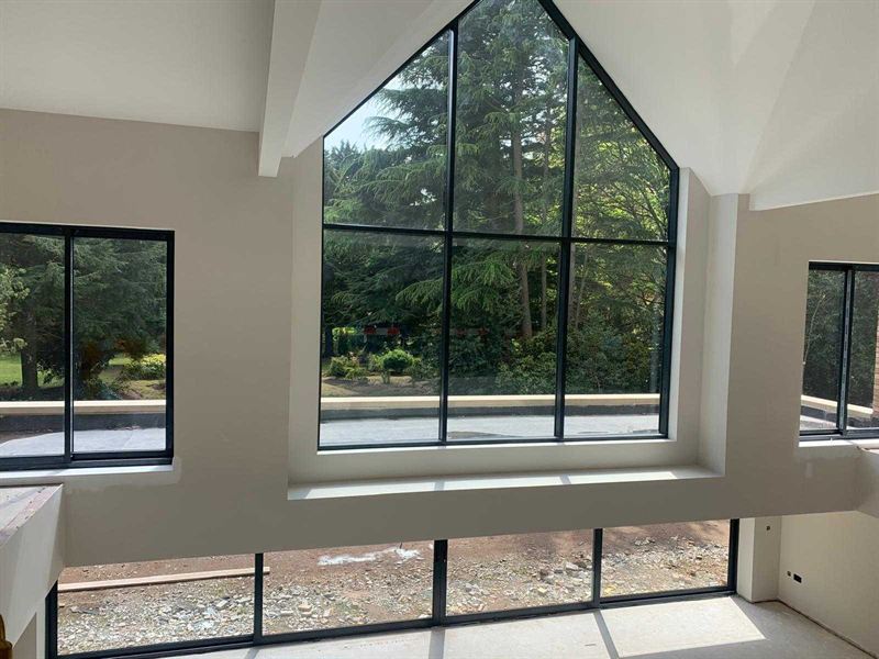 Full height gable glazing inside a new build, looking out over trees