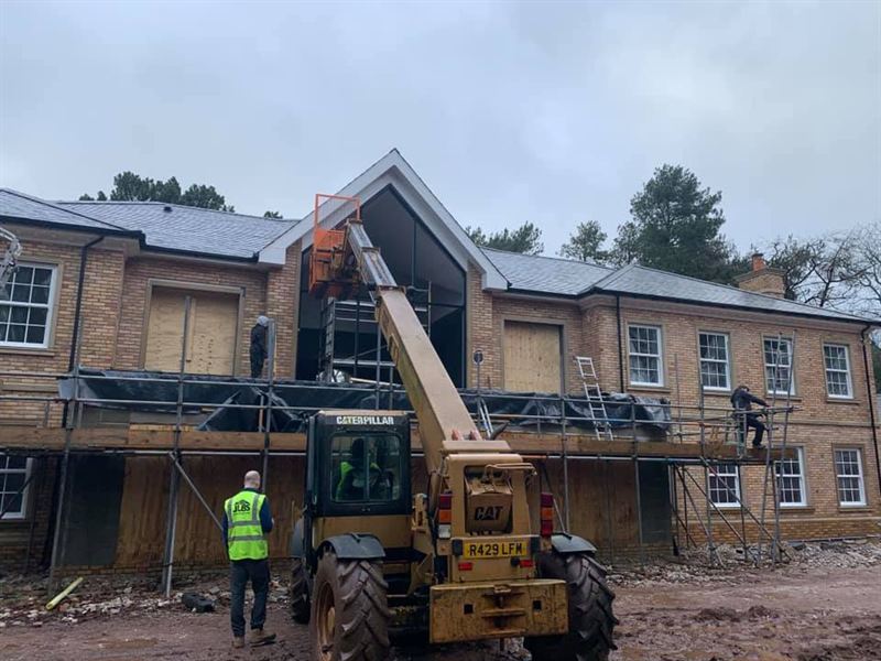 Telehandler lifting roof timbers into place on a two storey building site