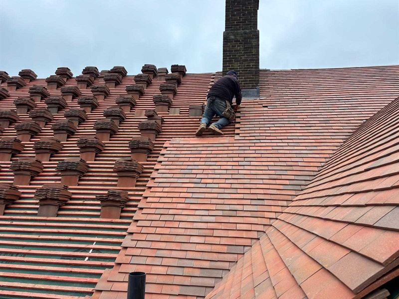 Roofer laying new tiles part way through a re-roofing job